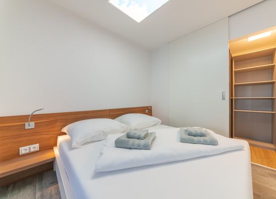 Schlafzimmer mit Doppelbett 160cm, dimmbaren Leseleuchten und Schiebetür zur Ankleide